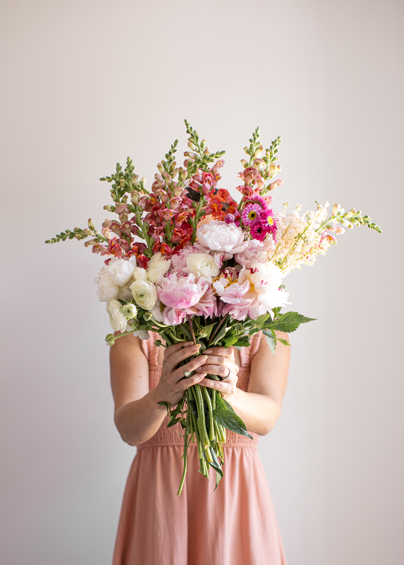 female holding a arge bunch of pink white and red flowers